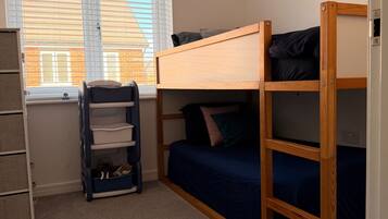 A bunk bed room with a window, a small shelf, and a ladder.