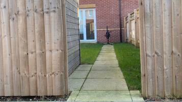 A residential property with a brick house, a wooden fence, and a paved driveway.