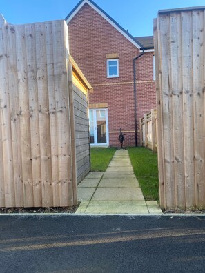 A residential property with a brick house, a wooden fence, and a paved driveway. - House Sleeps 6 With Garden and Parking (Doncaster)