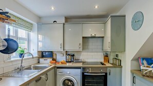 Une cuisine compacte équipée d’un lave-linge, d’un four et d’une fenêtre donnant sur un paysage agréable.