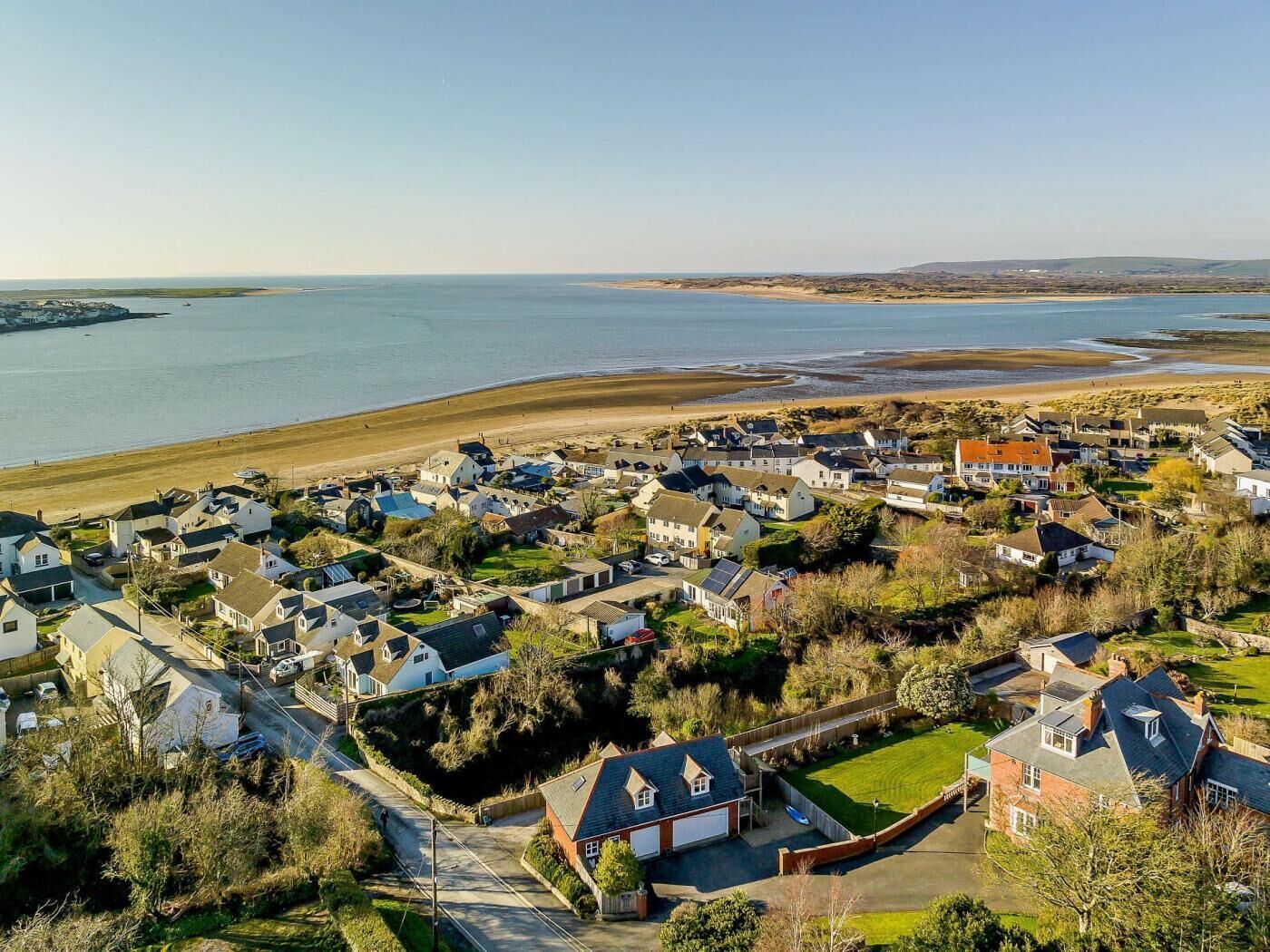 Un quartier résidentiel situé sur la côte, avec des maisons, une plage et une vue sur la mer.