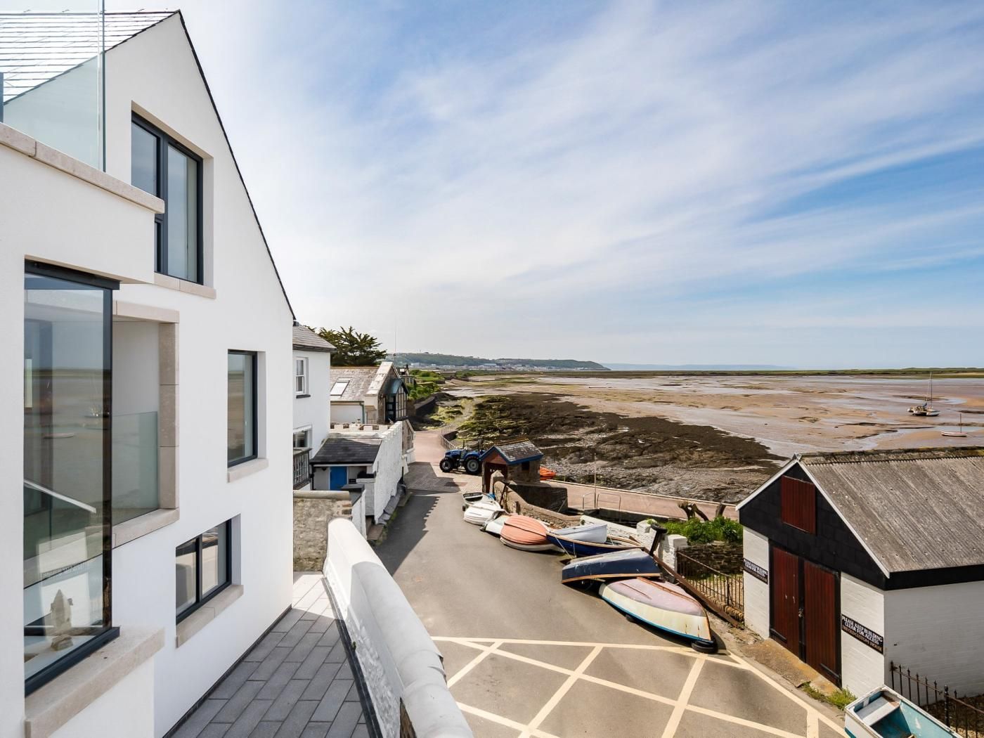 Un bâtiment moderne doté de grandes fenêtres donnant sur une plage où sont amarrés des bateaux.