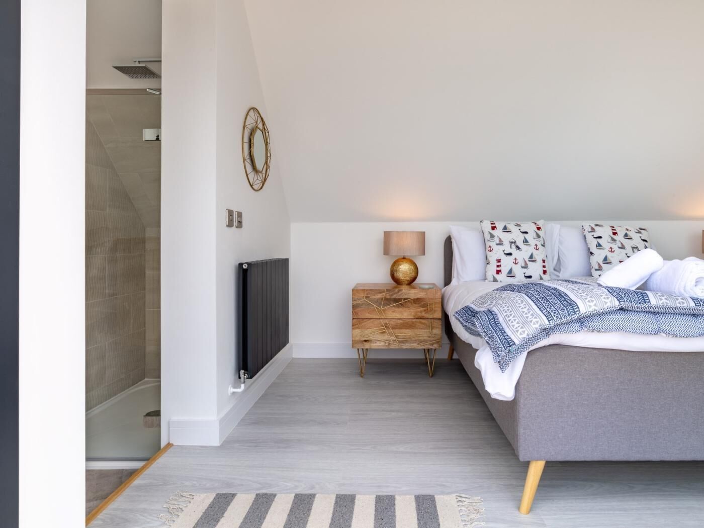A modern bedroom with a bed, bedside table, lamp, and a decorative wall piece.
