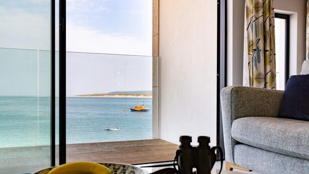 Ein Balkon mit Meerblick, eine Sitzecke, Ferngläser und ein Teller mit Bananen.