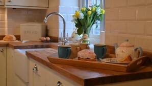 A kitchen with a wooden countertop, a sink, a vase with flowers, and a bread box. - 2 Bed in Ilminster (oc-56523) (Dowlish Ford)