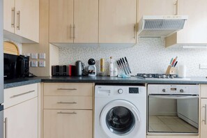 Une cuisine équipée d’un lave-linge, d’une cuisinière et d’un four à micro-ondes.