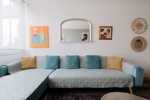 Een kamer met een bank, een spiegel en wanddecoratie.