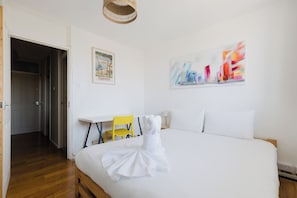Ein Hotelzimmer mit einem Bett, einem Sessel, einem Tisch und einer Tür zu einem anderen Raum.