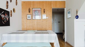 Una camera da letto con pannello di legno a parete, un letto con copriletto a quadretti e diverse decorazioni murali tra cui maschere e quadri incorniciati.