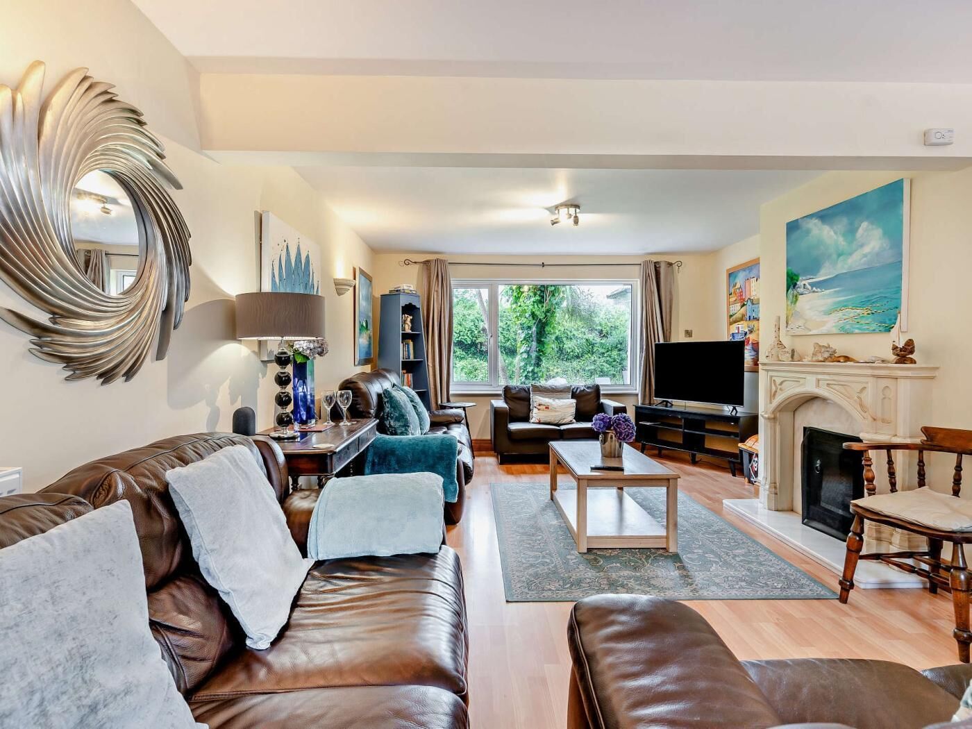 A living room with a fireplace, a television, and a large window.