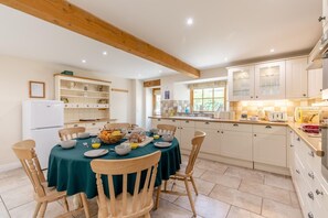 Eine moderne Küche mit weißen Schränken, einem Esstisch für vier Personen und einem Kühlschrank.