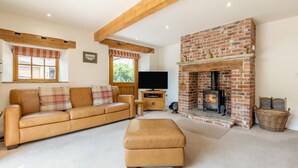 A cozy living room with a leather sofa, a television, and a brick fireplace. - 3 Bed in Buxton (oc-57037) (Cressbrook)