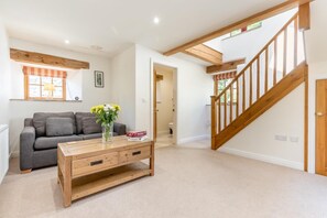 A living room with a sofa, a wooden coffee table, and a staircase. - 3 Bed in Buxton (oc-57037) (Cressbrook)