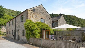 A stone building with a covered outdoor seating area and a view of a hillside. - 3 Bed in Buxton (oc-57037) (Cressbrook)