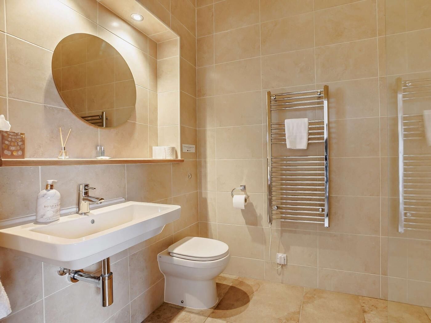 Une salle de bain moderne équipée d’un lavabo, de toilettes, d’un miroir et d’un porte-serviettes.