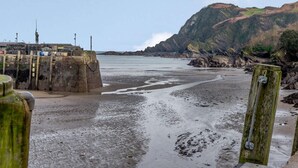 A coastal beach with a rocky cliff, a pier, and a sea wall. - 3 Bed in Ilfracombe (oc-57795) (Ilfracombe)