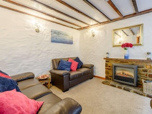 Ein gemütliches Wohnzimmer mit Kamin, Ledersofas und einer Steinwand.