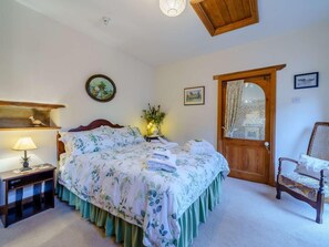 Ein Schlafzimmer mit Bett, Nachttisch, Lampe und einem Sessel.