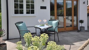 Eine Terrasse mit Tisch, Stühlen, einem Blumentopf und einer Tür mit Glasfenstern.