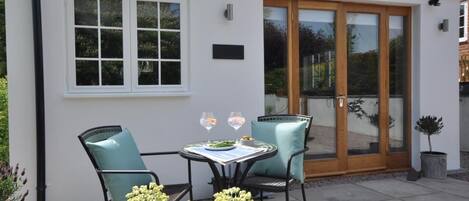 A patio with a table and chairs, a potted plant, and a door with glass panels.