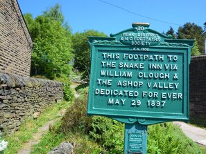 Ein grünes Schild mit weißer Schrift, das auf einen Fußweg zur Snake Inn über William Clough und das Ashop Valley verweist, datiert vom 29. Mai 1897.