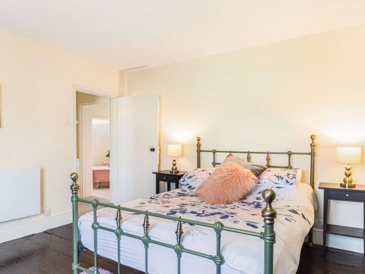 A bed with a metal frame, a floral bedspread, and two bedside lamps.