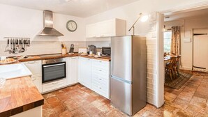 Una cocina moderna con armarios blancos, un refrigerador de acero inoxidable, un horno y un reloj en la pared.