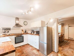 A modern kitchen with white cabinets, a stainless steel refrigerator, an oven, and a clock on the wall. - 3 Bed in York (oc-57964) (Stillingfleet)