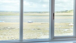 Blick durch ein Fenster auf einen Fluss mit Booten am Ufer.