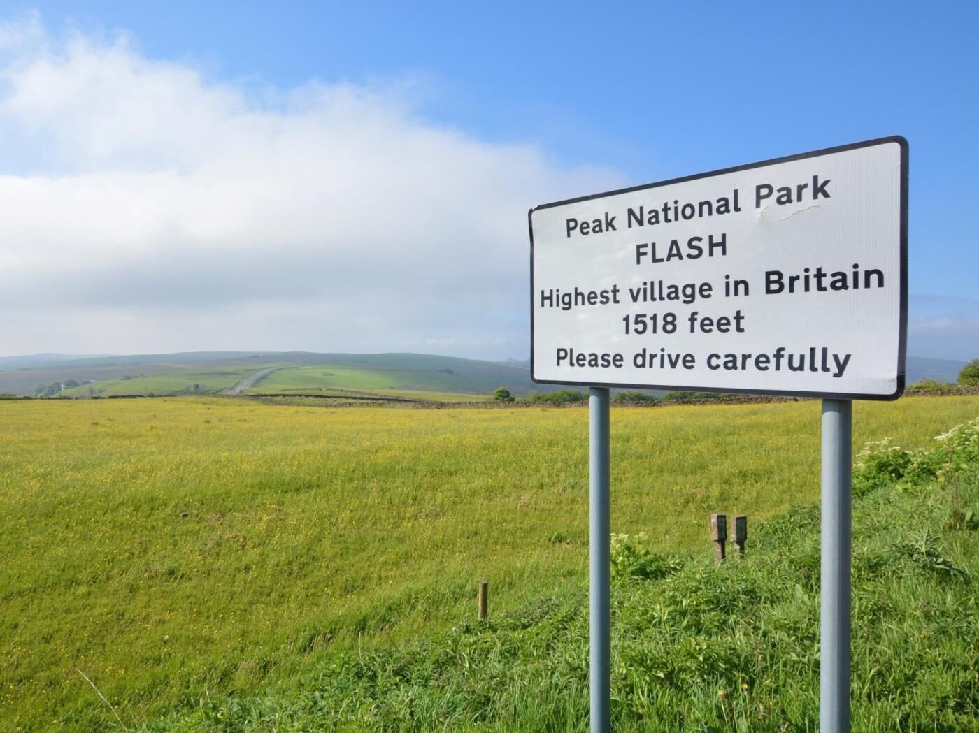 Skilt for Peak National Park og Flash, der nævner det som den højeste landsby i Storbritannien i 463 meters højde, med en opfordring til forsigtig kørsel.