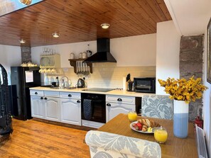 Une cuisine moderne avec des meubles en bois, un réfrigérateur noir, un four à micro-ondes et un coin repas avec une table mise pour le petit-déjeuner.