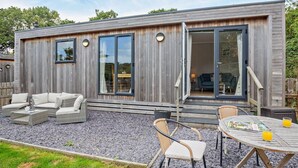 Uma casa moderna com área de pátio, mobiliário de exterior e uma grande porta de correr de vidro.