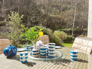 A round glass table with striped blue and white cups, a white vase with yellow flowers, and a blue teapot. - 3 Bed in Bideford (oc-60643) (Buck's Mills)