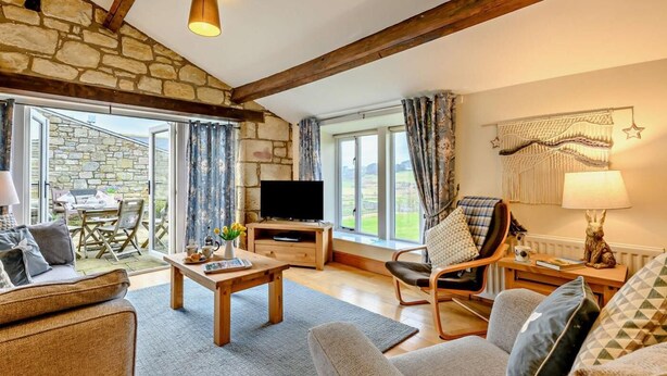 A cozy living room with stone walls, a flat-screen TV, a wooden coffee table, and a comfortable sofa. - 2 Bed in Morpeth (oc-61267) (Rothbury)