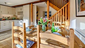 A dining area with a wooden table set for two, a staircase, and a kitchen in the background. - 2 Bed in Morpeth (oc-61267) (Rothbury)
