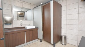 Ein modernes Badezimmer mit einem Holzkonsolenunterschrank, einem Spiegel, einem Waschbecken und einer Toilette.