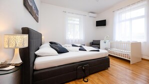 A bedroom with a bed, bedside lamp, TV, crib, and a window with curtains. - Gorgeous home in Slatine with WiFi (Slatine)