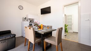 A modern kitchen with a dining table, chairs, a coffee machine, and a TV mounted on the wall. - Gorgeous home in Slatine with WiFi (Slatine)