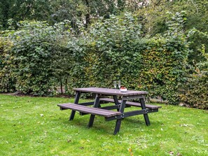 A picnic table with benches in a grassy area surrounded by dense foliage. - 4 Bed in Swanage (oc-62985) (Worth Matravers)