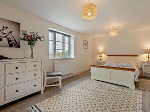 A bedroom with a bed, bedside tables, a dresser, a window, and a hanging light fixture. - 4 Bed in Swanage (oc-62985) (Worth Matravers)