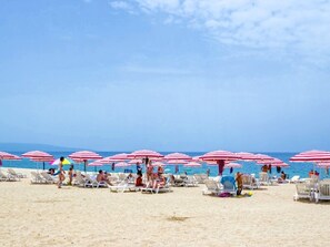 A beach with rows of sun loungers and red and white striped umbrellas. - Casa Onde Chiare - Pizzo Beach Club 16G (Contrada Difesa II)