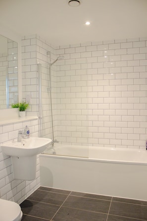 A bathroom with white tiled walls, a white sink, a bathtub, and a shower. - Effortless Stays at 2BR Escape OldTrafford Stadium (Stretford)