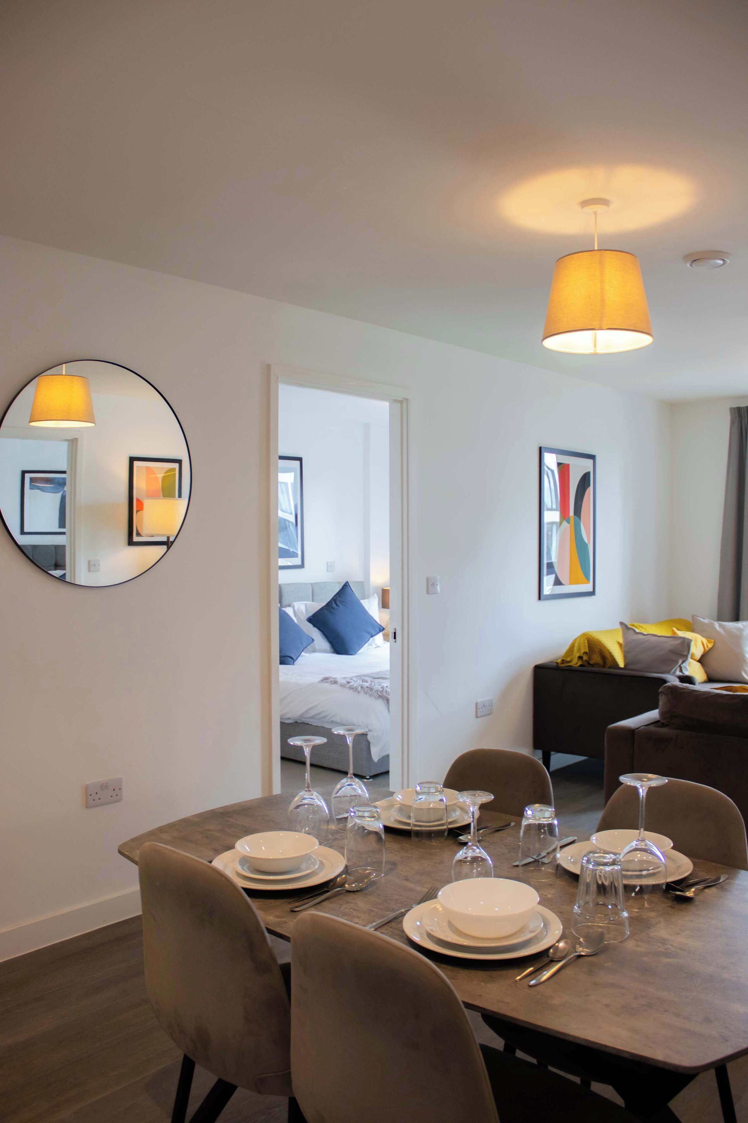 A modern hotel room with a dining area, a bed, and a living area.
