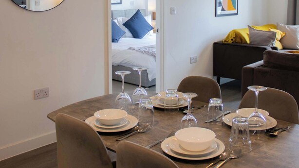 Moderni hotellihuone, jossa on ruokailutila, sänky ja oleskelualue.