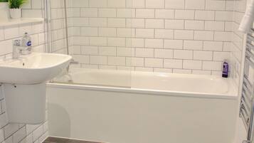 Een badkamer met een wit bad, een wastafel en een toilet.