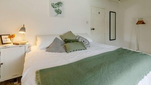 Una camera da letto con un letto, un comodino, una lampada e un quadro appeso al muro.