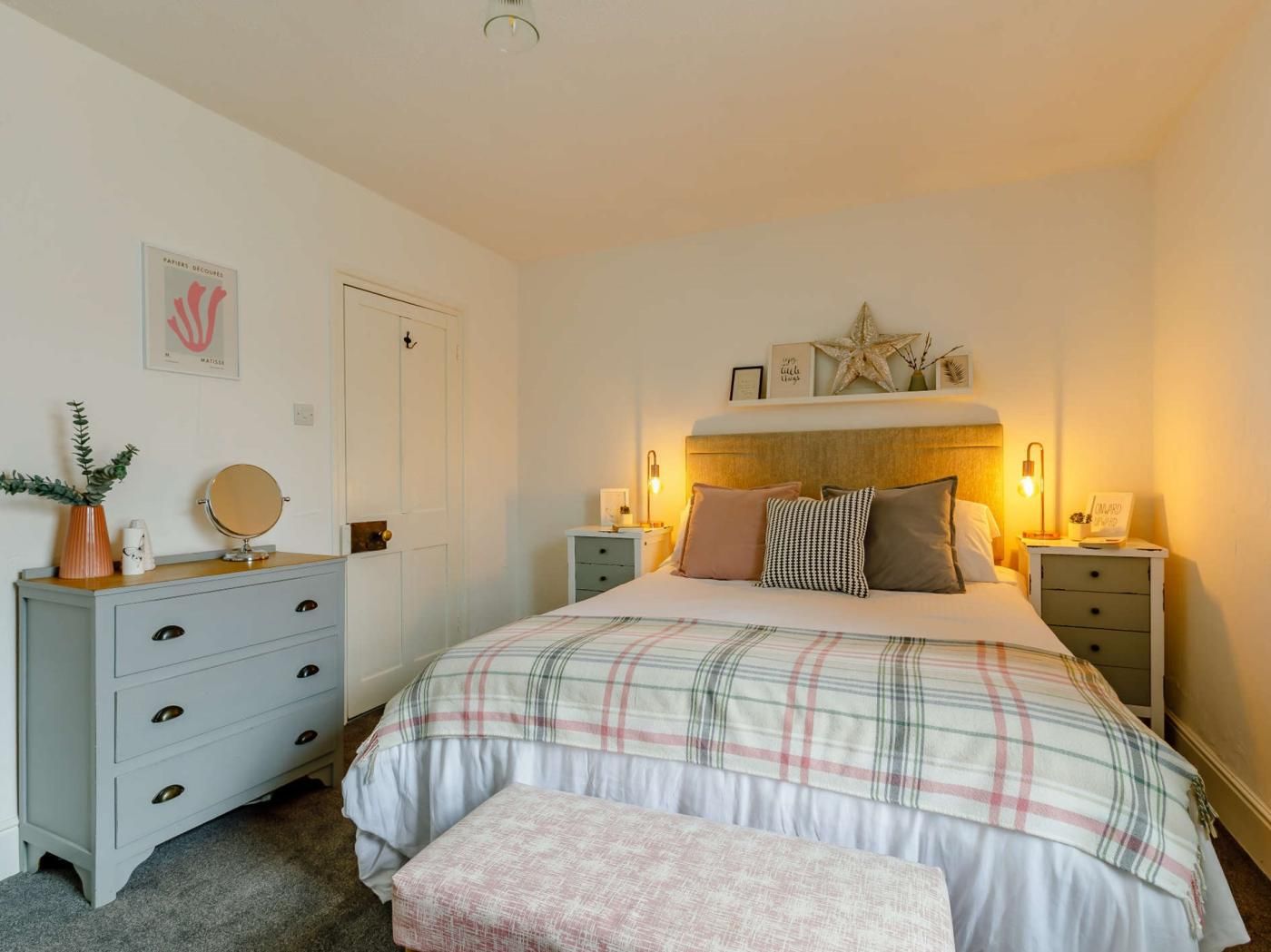 Une chambre à coucher avec un lit, des tables de chevet, une commode et une porte.