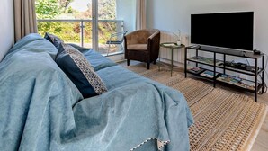 A modern living room with a sofa, a chair, a TV, and a small table. - 2 Bed in Newquay (oc-63267) (Newquay)