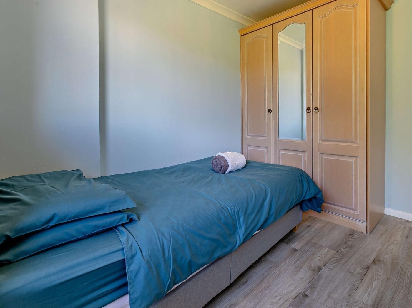 Un dormitorio con cama, armario y espejo.