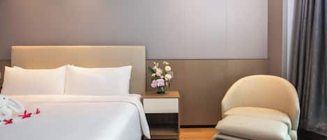 Habitación de hotel con una cama grande, una mesita de noche con un florero, una silla y un panel de pared moderno.